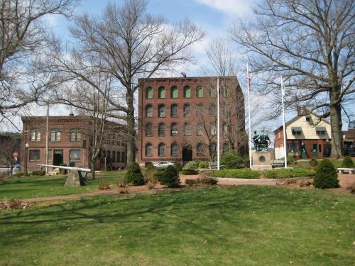 Buildings sitting behind a green space with trees and bushes